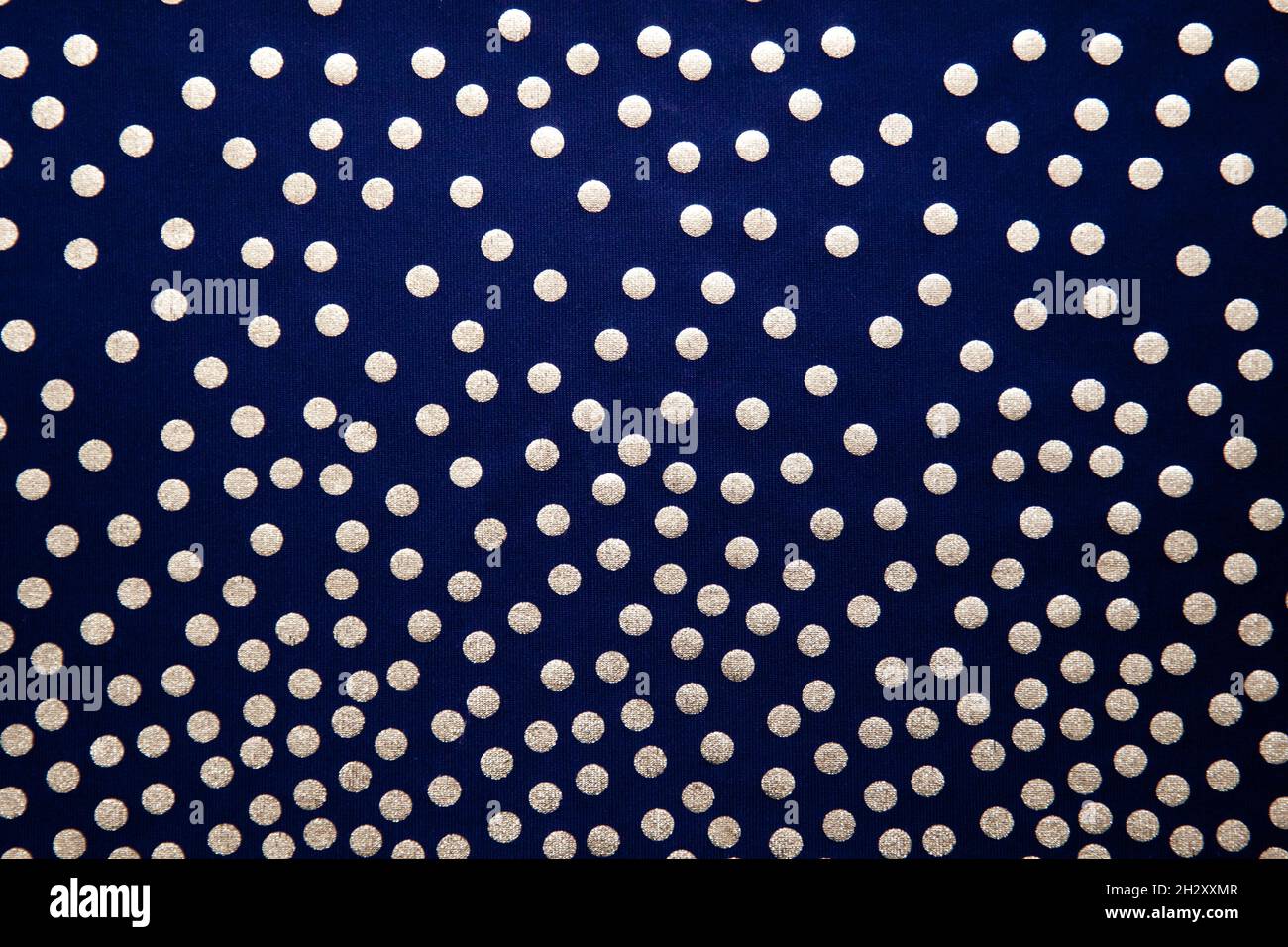 Punti dorati su sfondo scuro. Sfondo blu scuro con puntini di polka, tessuto con motivo. Foto Stock