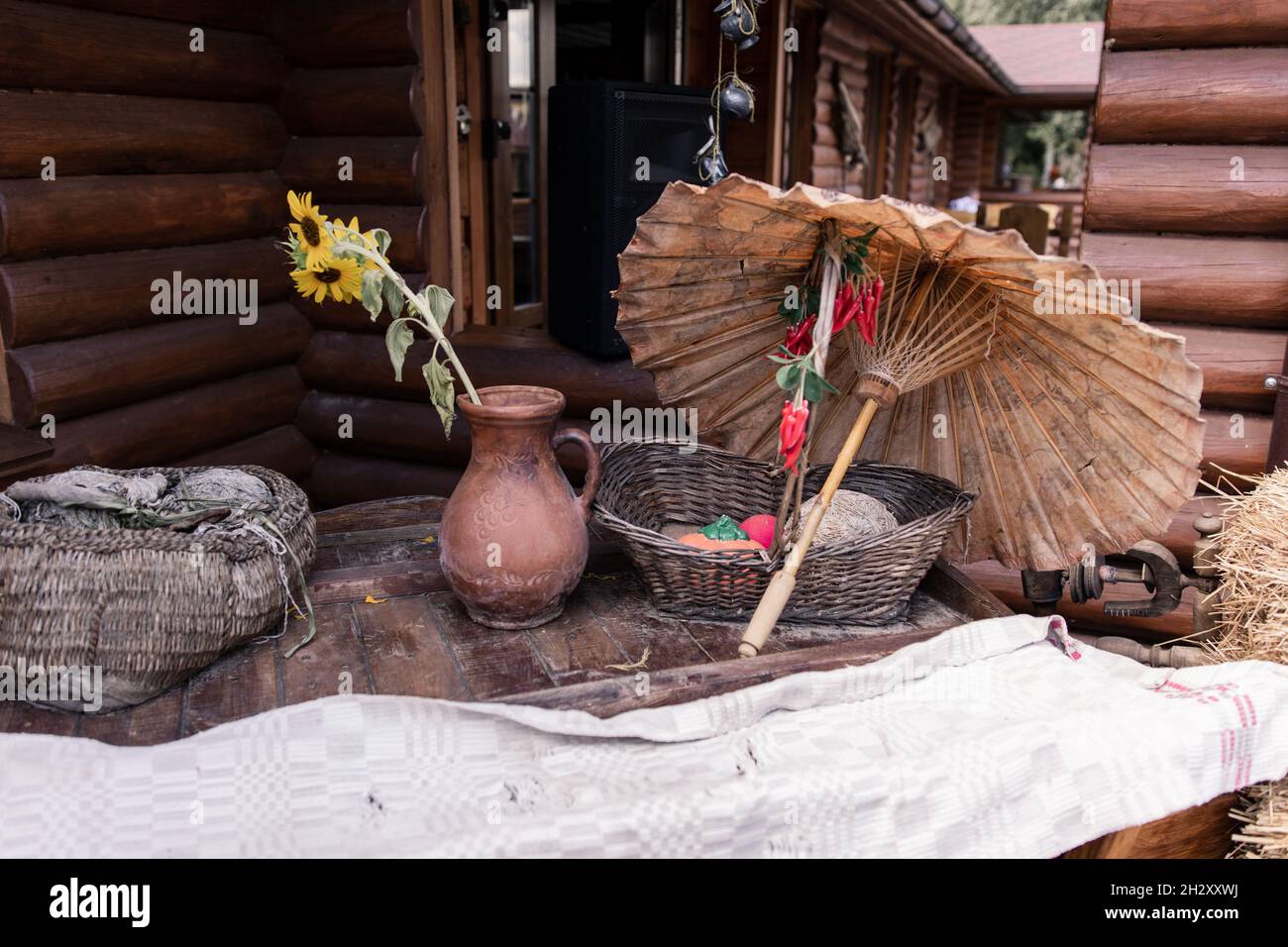 un vaso di argilla e ombrello di paglia vicino ad una casa di legno Foto Stock