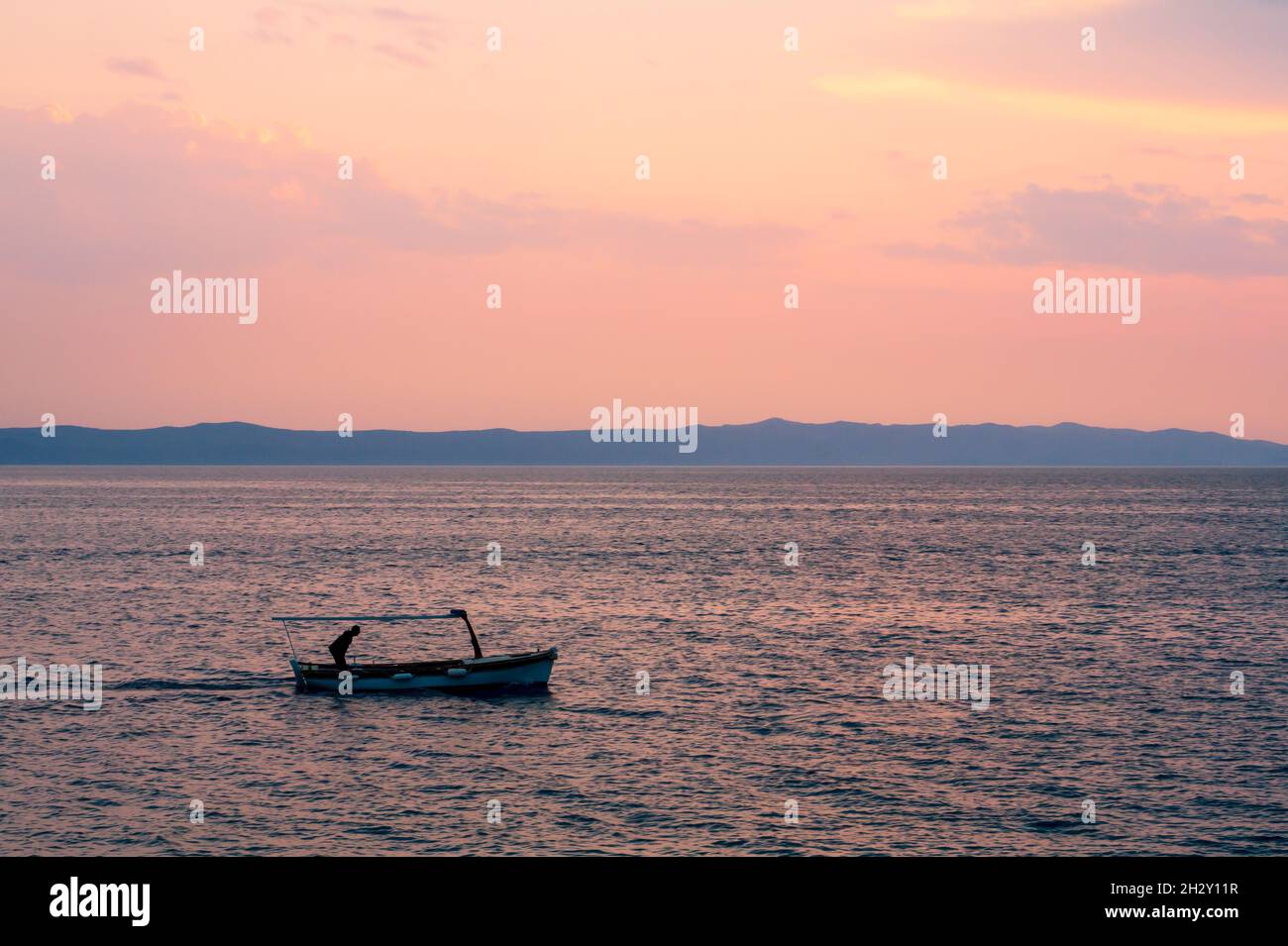 Fisher con la sua barca al tramonto Foto Stock