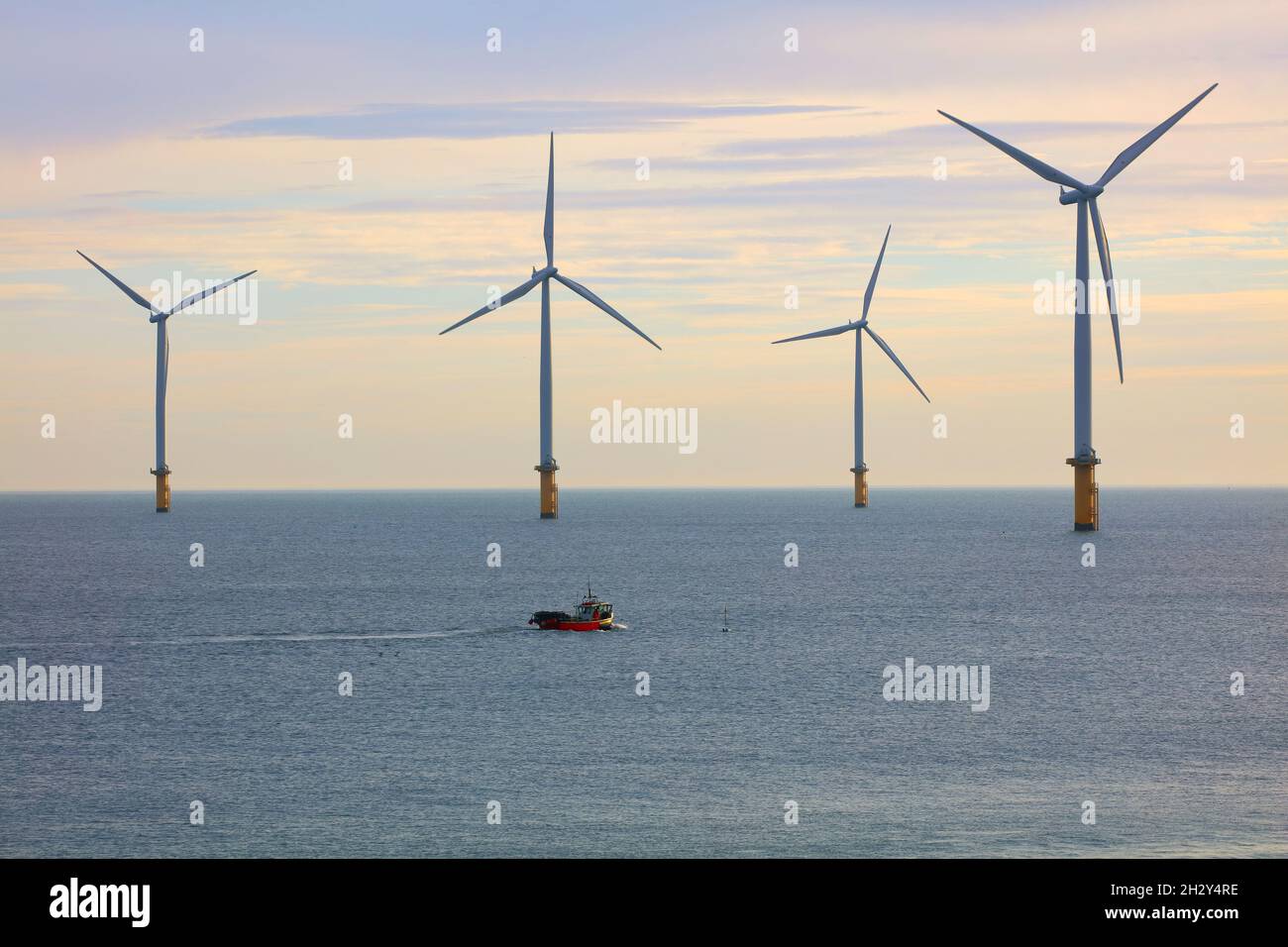 Piccola barca da pesca oscura da enormi turbine eoliche al largo della costa nord-orientale, Redcar, North Yorkshire, Inghilterra, Regno Unito. Foto Stock