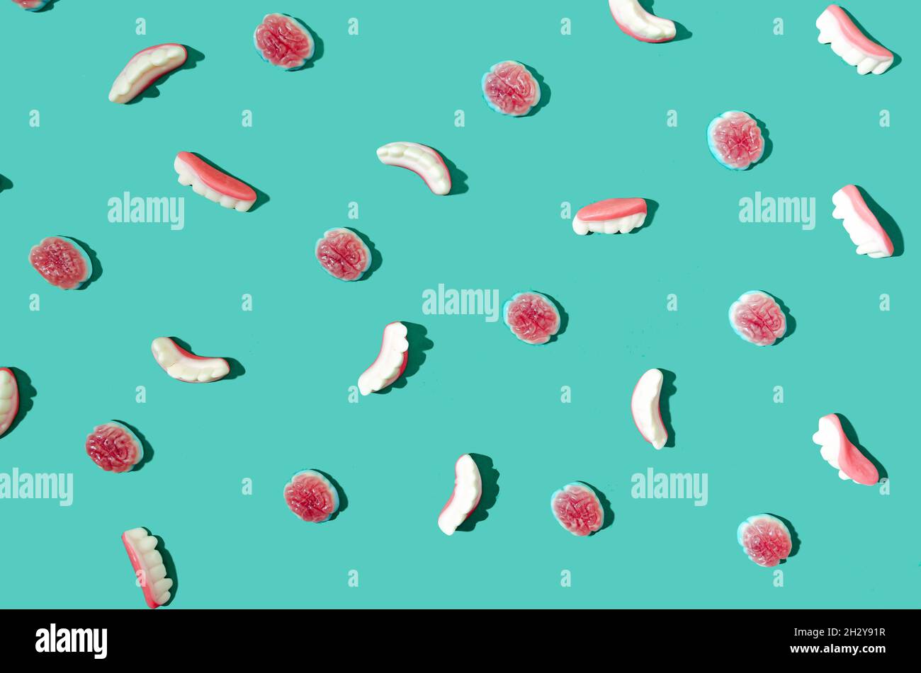 Una carta da parati o sfondo fatto di fagioli di gelatina a forma di cervello umano e teeti umani su sfondo verde. Divertente o spoky Halloween concetto per Foto Stock