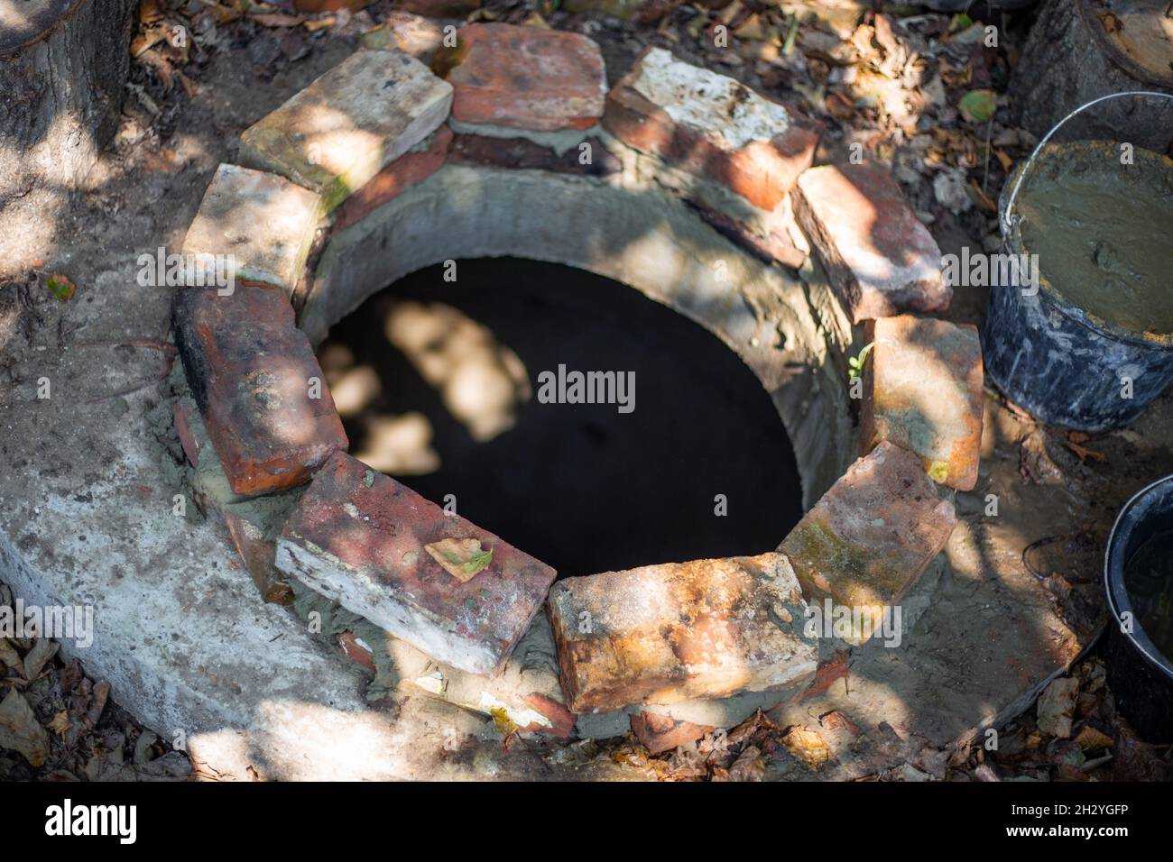 Posa di mattoni la bocca di un pozzo settico. Lavoro con cemento, costruzione di un serbatoio settico. Foto Stock