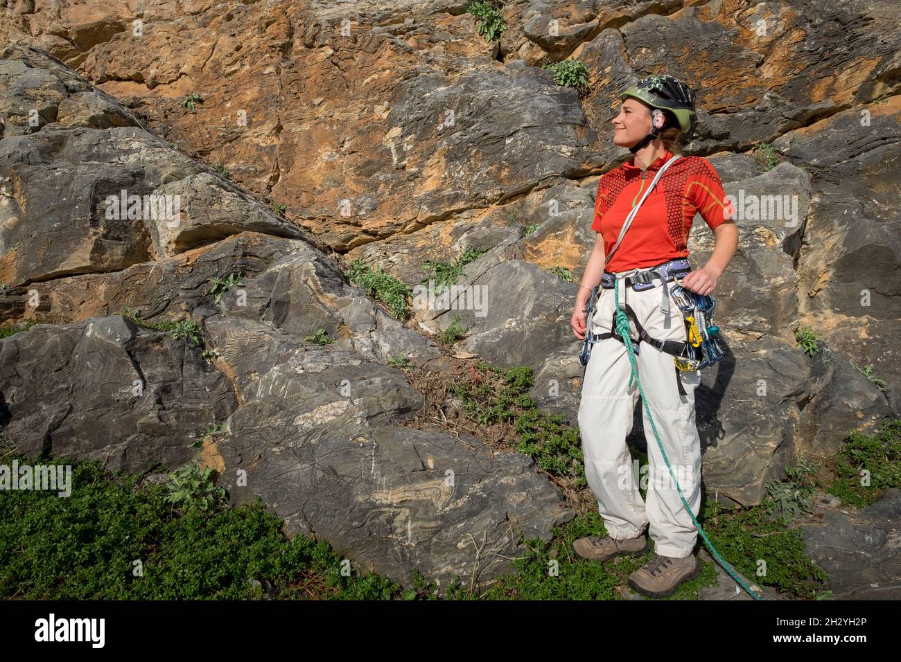 Arrampicatore femminile con clim e posizionamento di attrezzatura di sicurezza per arrampicata nella roccia Foto Stock