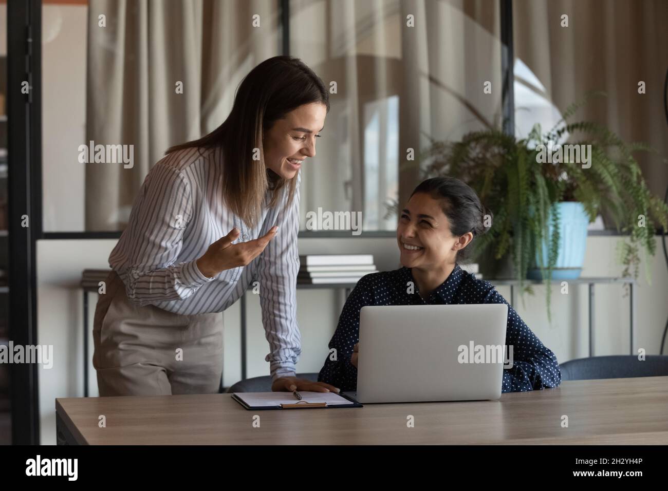 Due colleghi di sesso femminile di diverse etnie discutono il lavoro sul posto di lavoro Foto Stock