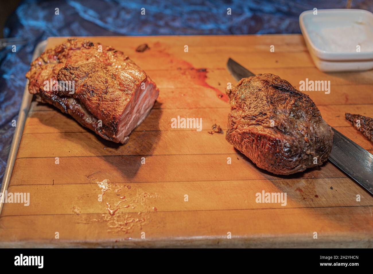 Manzo arrosto Grassfed su tagliere di legno con sale e coltello da cucina Foto Stock