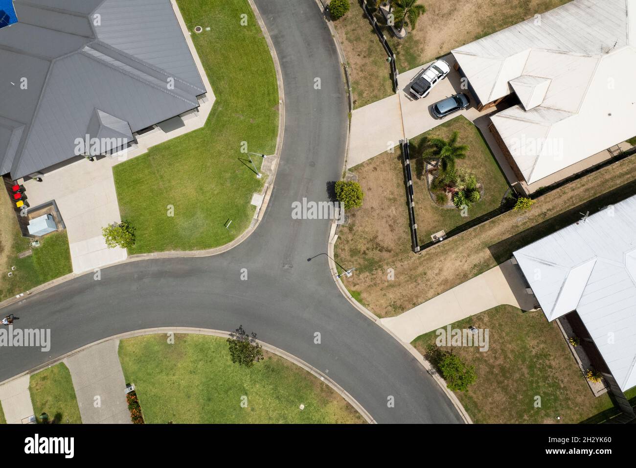 Antenna drone di case suburbane con auto parcheggiate in vialetti, giardini e strada Foto Stock