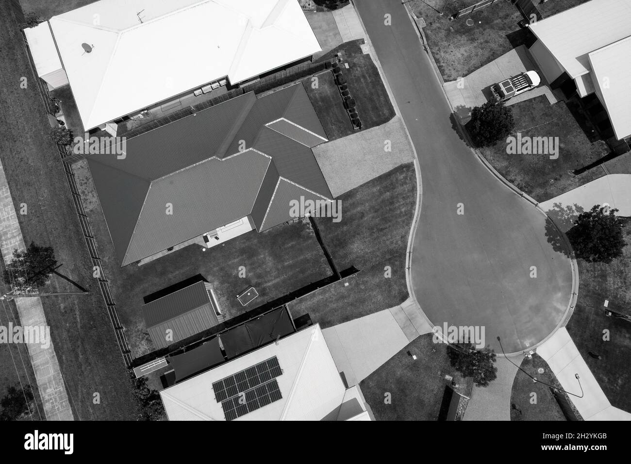 Antenna drone di case suburbane con auto parcheggiate in vialetti, giardini e strada Foto Stock