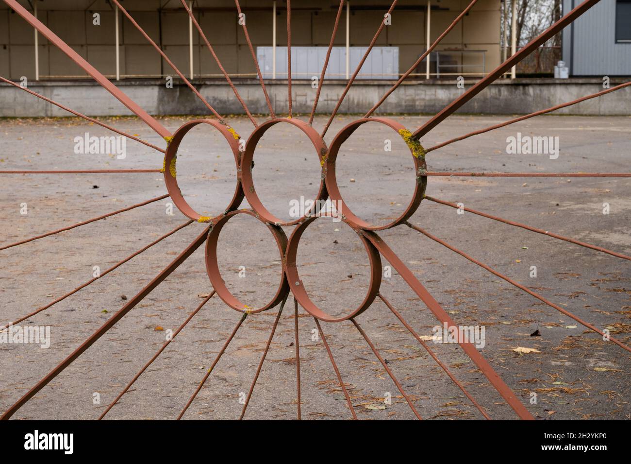 Vecchio cancello di metallo coperto di muschio all'area di magazzino sotto forma di cerchi olimpici. Foto Stock