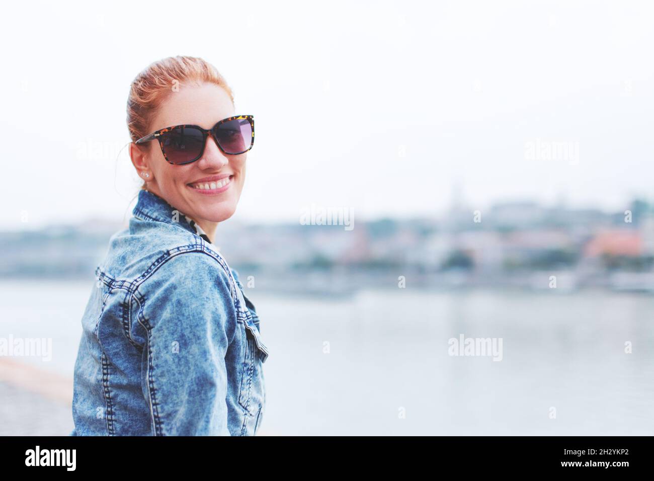 Felice giovane rossa caucasica donna toothy sorriso a riva al fiume Foto Stock