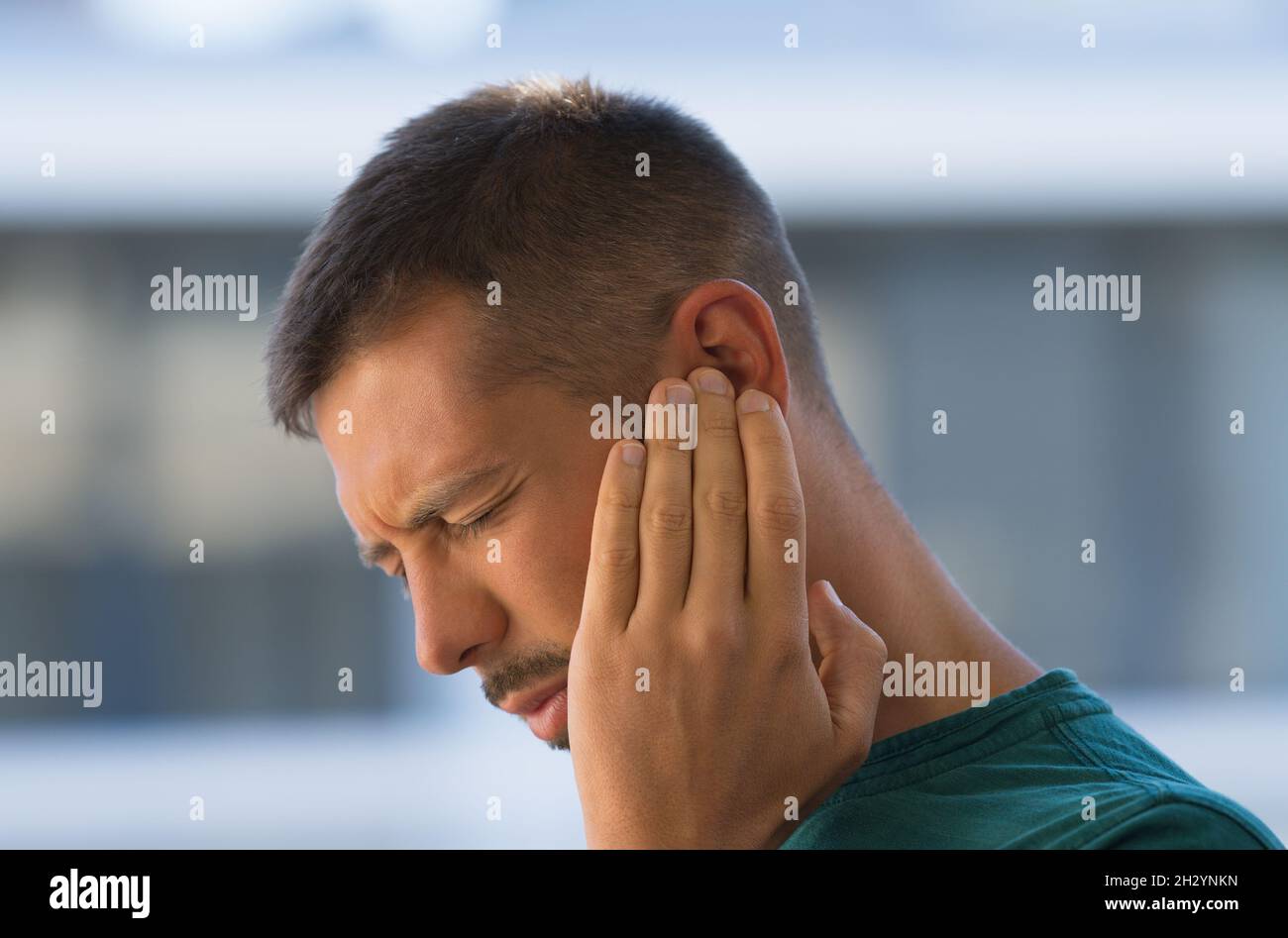 Giovane con orecchi, otite o tinnito. Infiammazione dell'orecchio. Uomo che soffre di dolore all'orecchio Foto Stock
