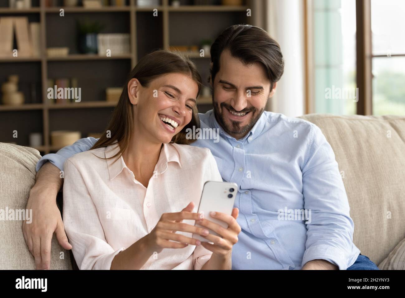 Felice giovane coppia di famiglia che usa il cellulare a casa. Foto Stock