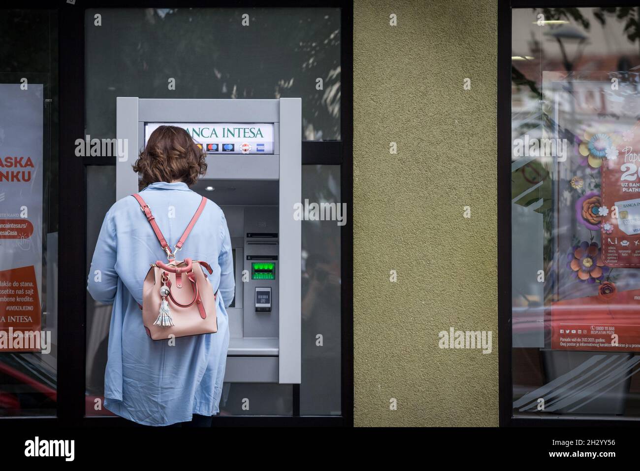 Foto di una donna che utilizza i servizi di Banca intesa, prelevando contanti e denaro nel centro della città di Belgrado, serbia, utilizzando un bancomat. Foto Stock