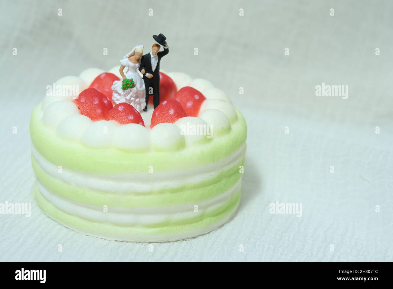 Sposarsi e sposarsi sopra la torta con sfondo bianco sfocato. Foto immagine Foto Stock