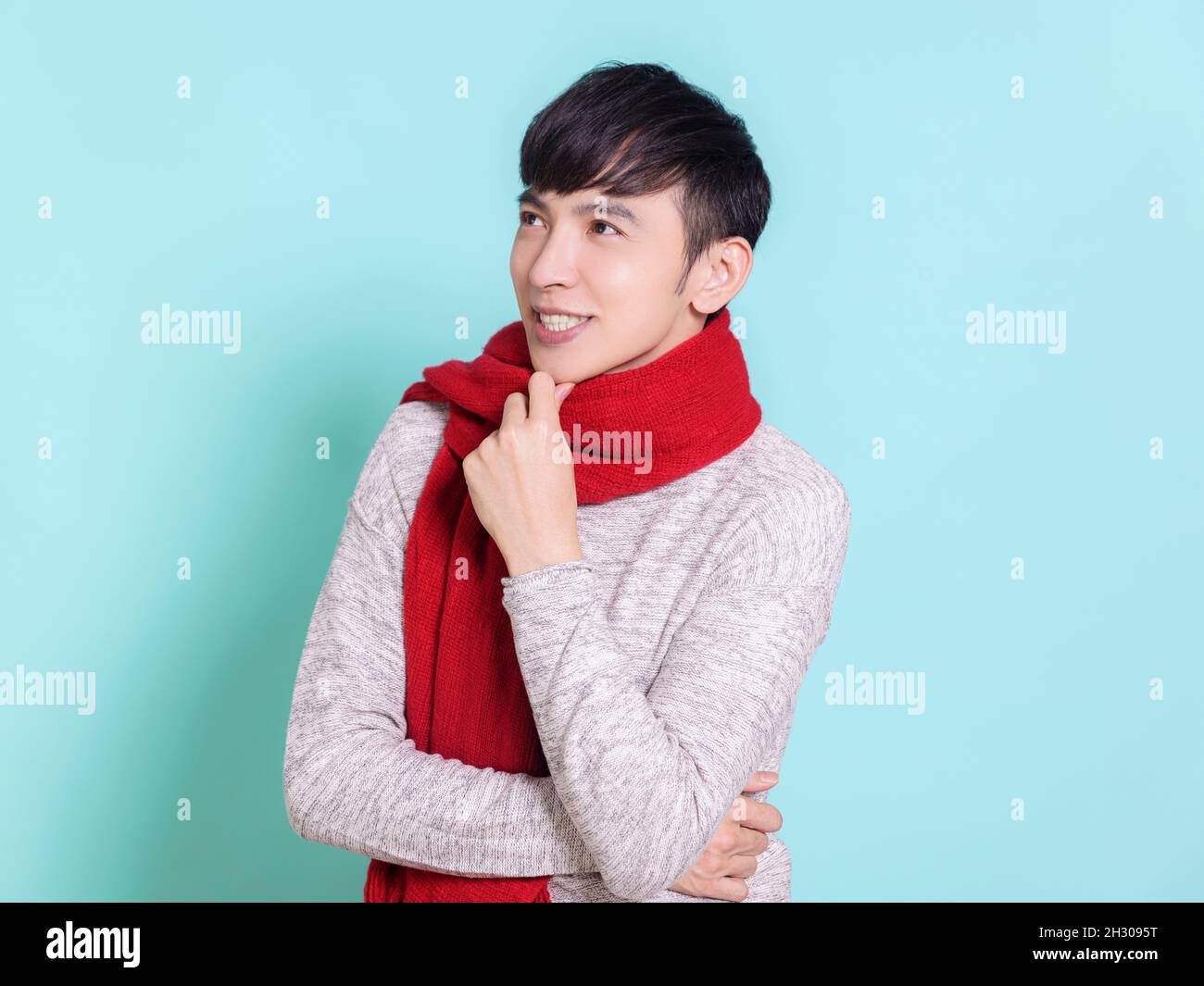 Bel giovane uomo che indossa una sciarpa rossa, pensando e guardando sopra.isolato su sfondo blu. Foto Stock