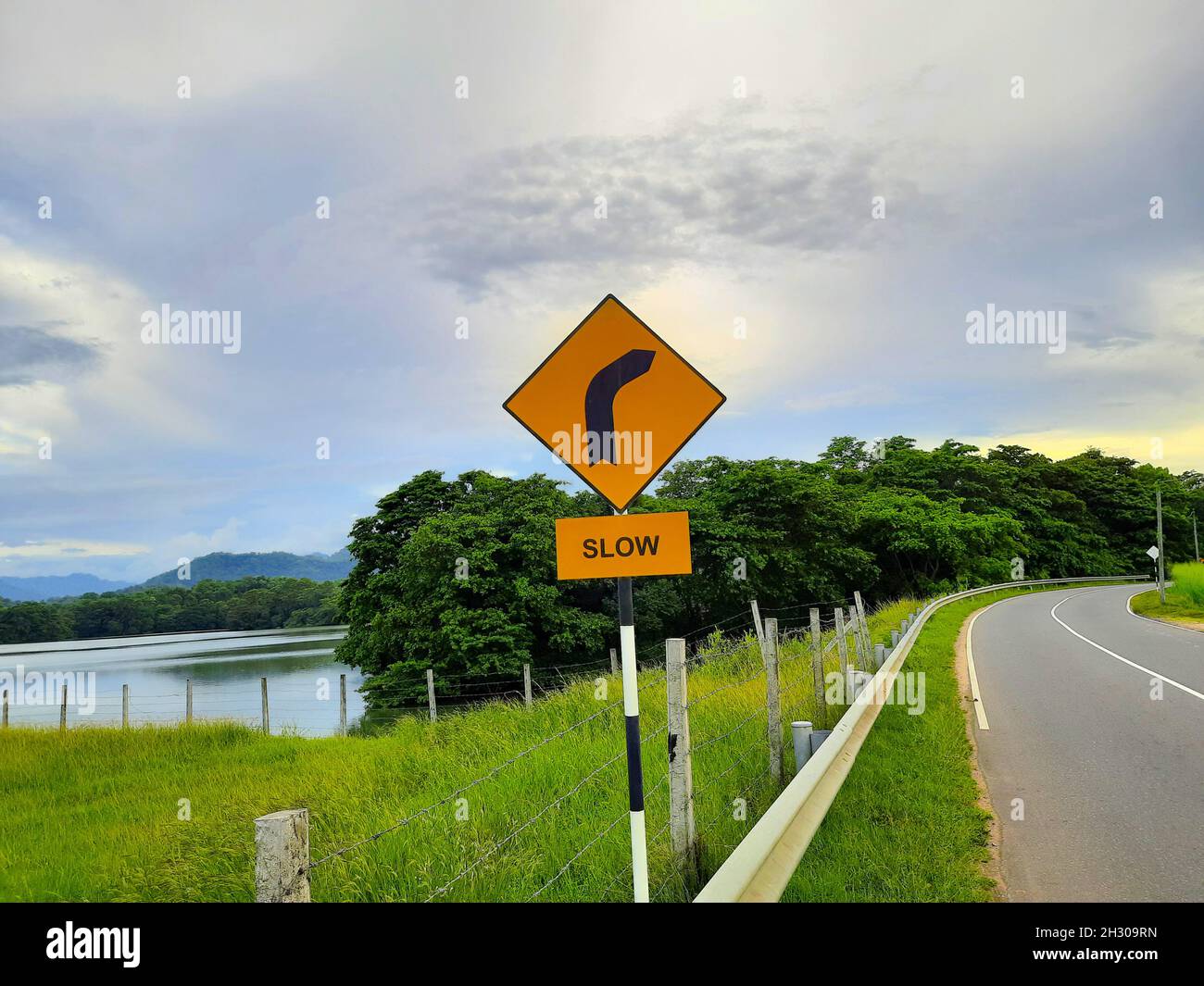 Lento e una curva a destra segno nell'angolo sinistro della strada Foto Stock