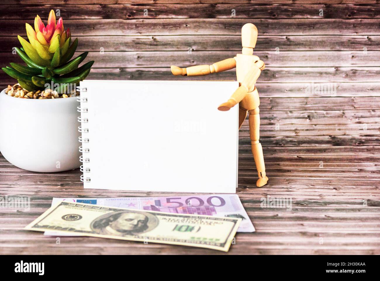 Blocco note e denaro sul tavolo. Blocco note per la scrittura, euro e dollari su uno sfondo di legno scuro. Concetto di pianificazione aziendale e di viaggio. Foto Stock