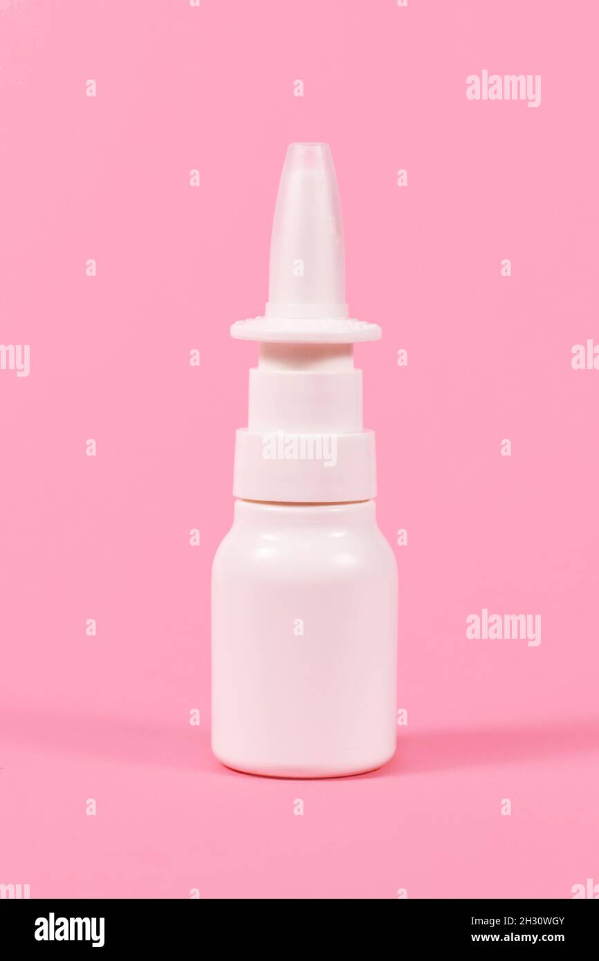 Flacone spray nasale bianco su sfondo rosa Foto Stock