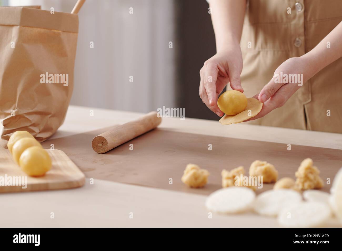 Immagine ravvicinata della donna che si riempie con un sottile pezzo di pasta quando si fa la torta alla luna a casa per la festa tradizionale Foto Stock