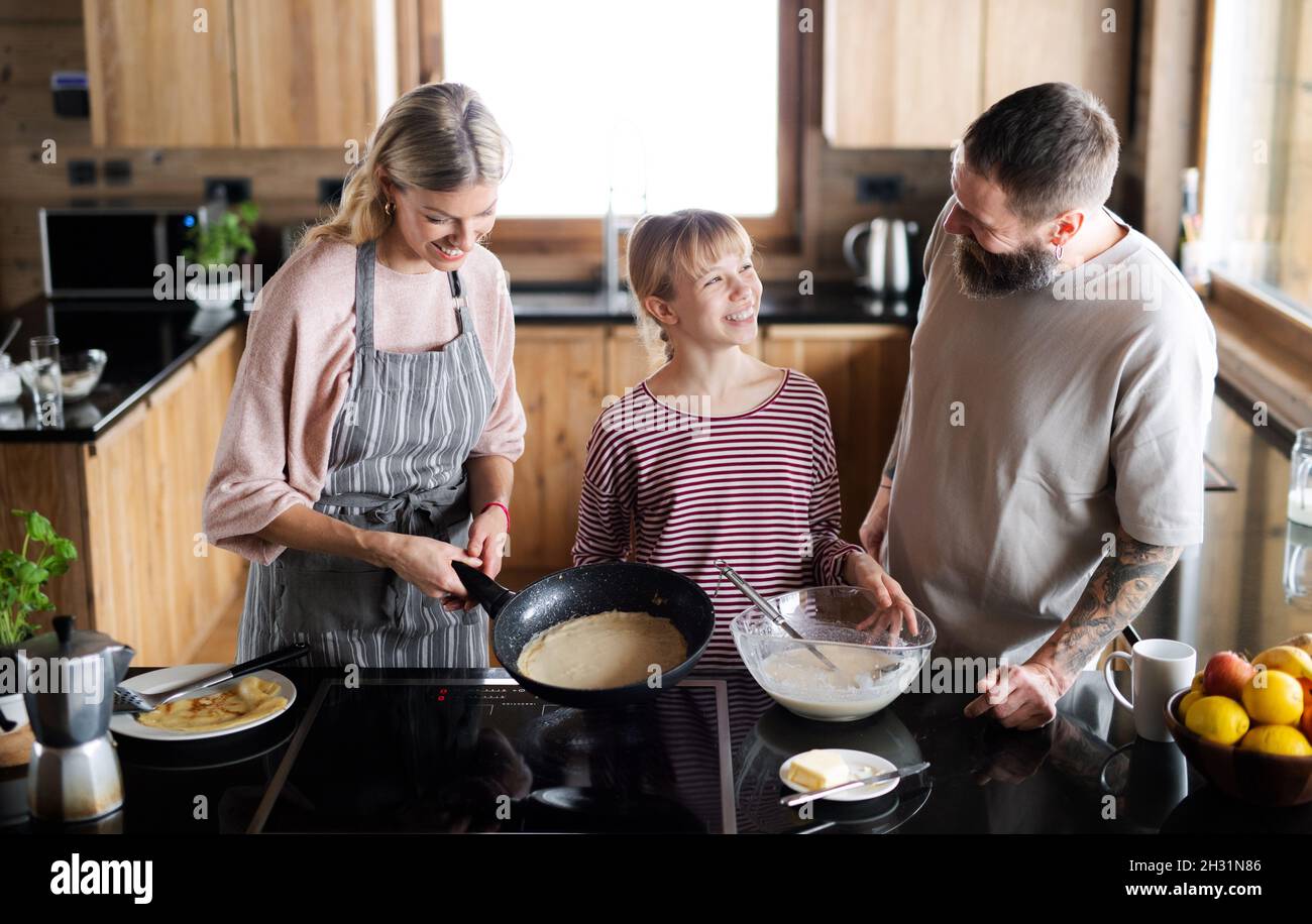 Famiglia con piccola figlia cucina interna, vacanza invernale in appartamento privato. Foto Stock