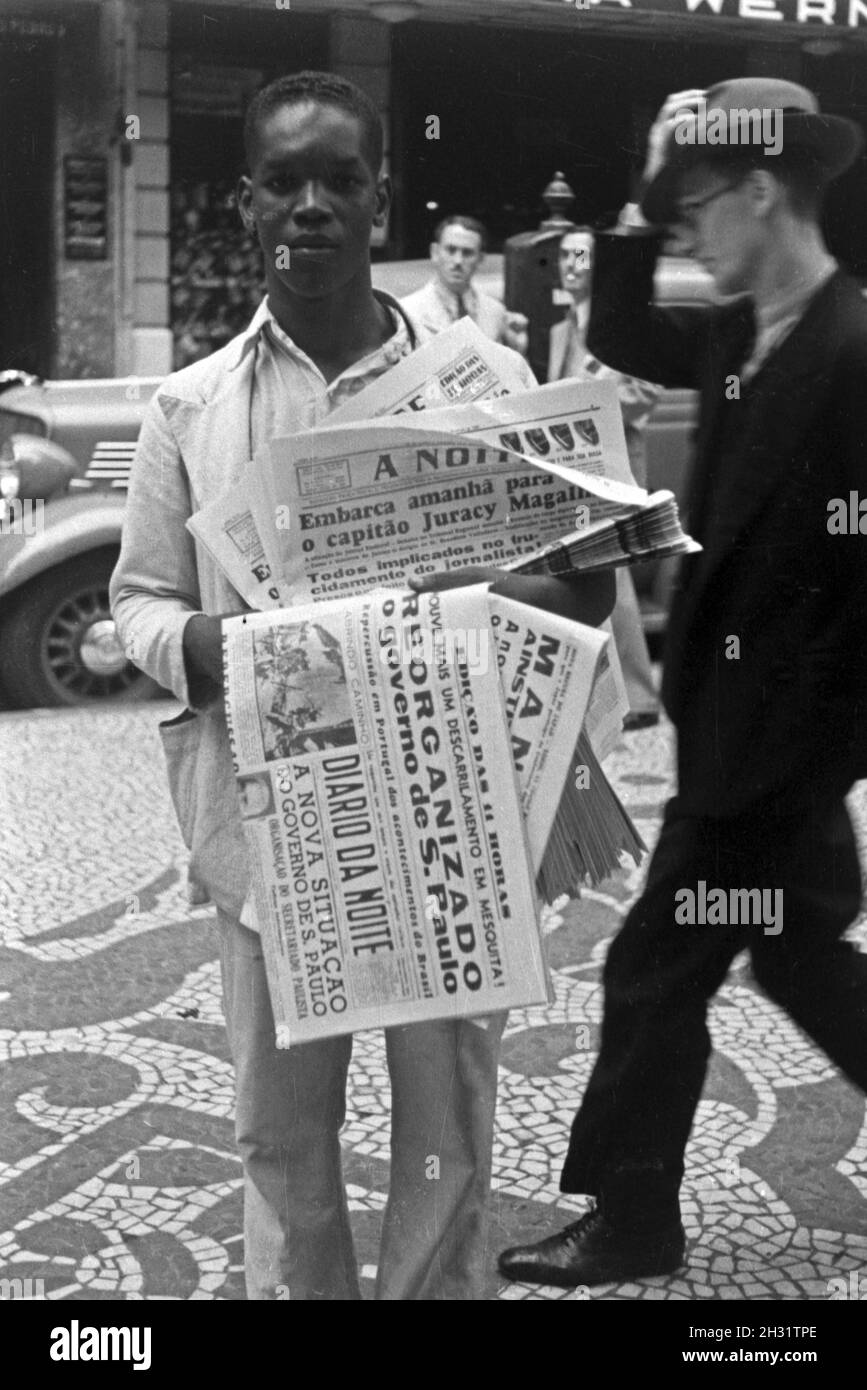 Auf der Heimreise von der Walfischjagd geht die Besatzung des Fabrikschiffs 'Jan Wellem' auf Landgang duch Rio de Janeiro und fotografiert einen Zeitungsverkäufer, Brasilien 1930er Jahre. Congedo a terra l'equipaggio della nave officina 'Jan Wellem' a Rio de Janeiro dove prendono la foto di un ragazzo della carta, Brasile 1930s. Foto Stock