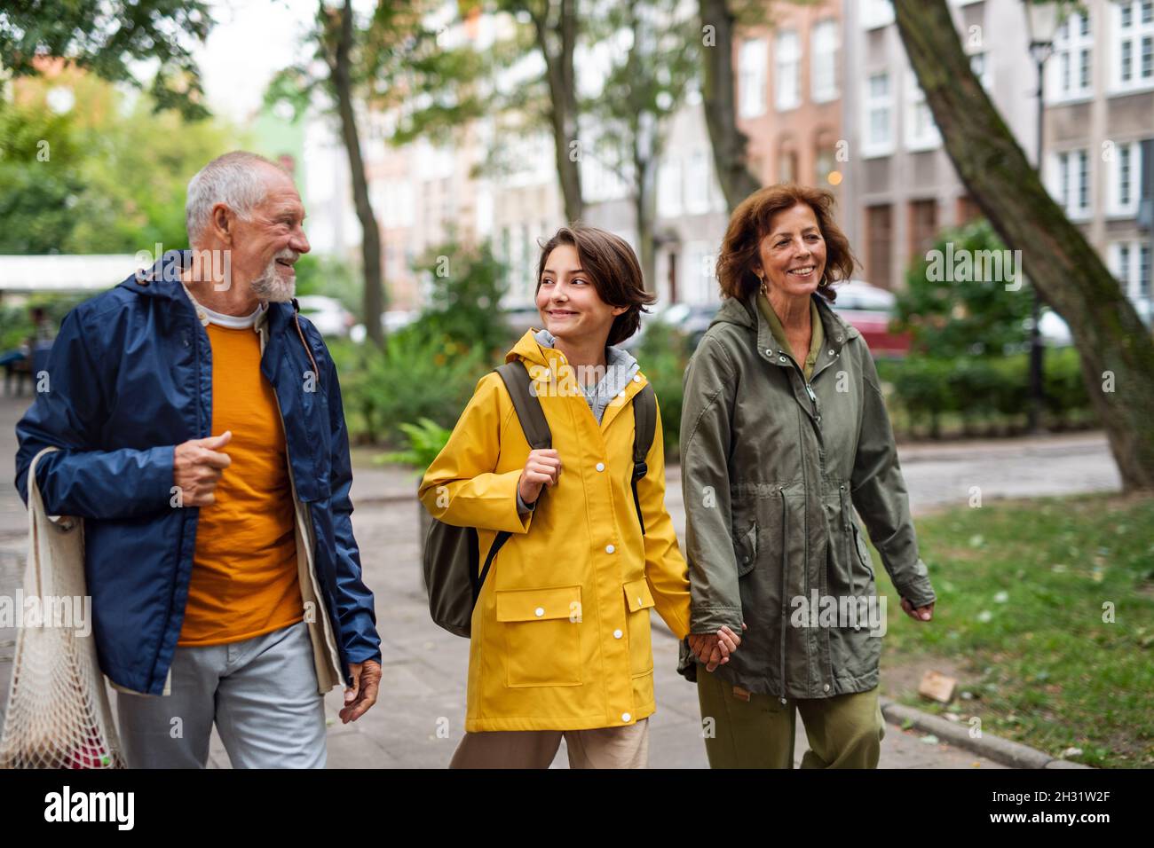 Ritratto di nonni felici con nonno di preteen che cammina insieme portelli in strada della città Foto Stock