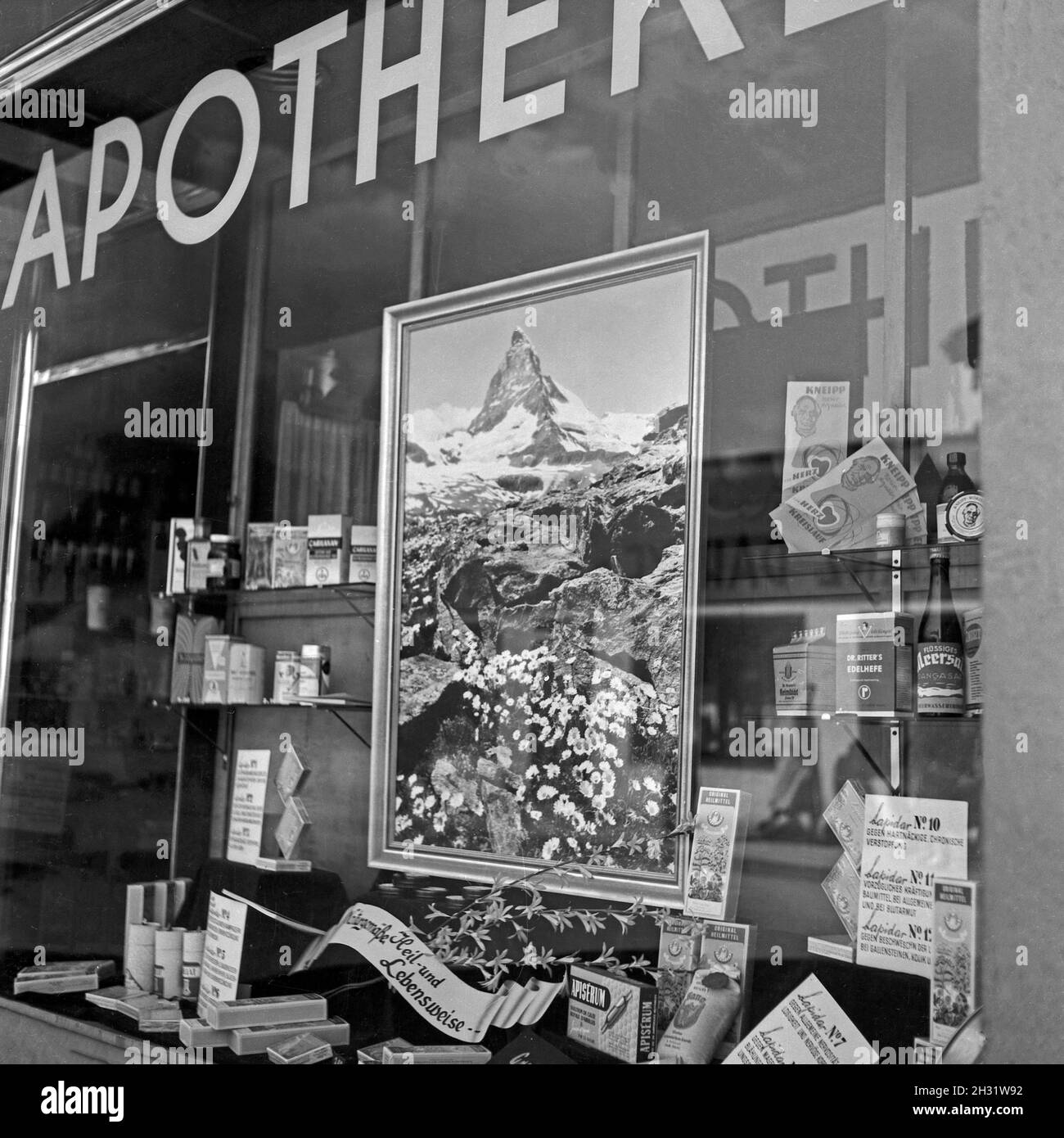 Auslage und ein Bild vom Matterhorn im Schaufenster einer Apotheke, Deutschland 1958. Vista su una vetrina di una farmacia, Germania 1958. Foto Stock