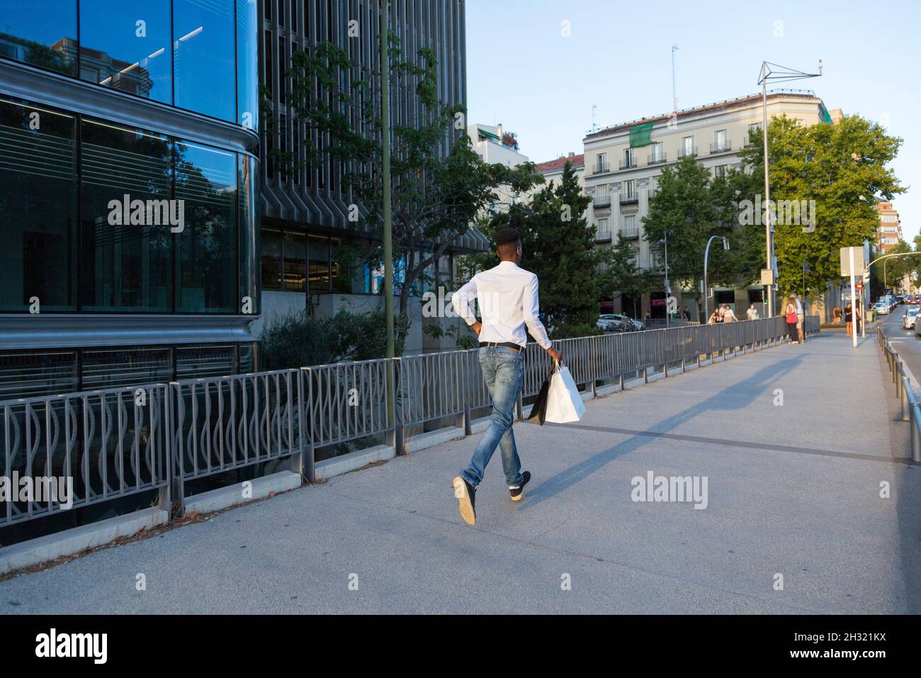 giovane afro che corre per strada con borse di carta in mano Foto Stock