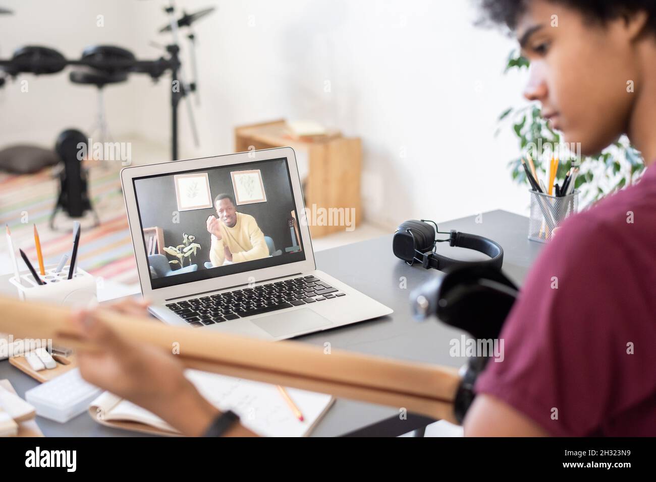 Insegnante di musica fiducioso che consulti ragazzo con la chitarra seduta di fronte al laptop in ambiente domestico durante la lezione online Foto Stock