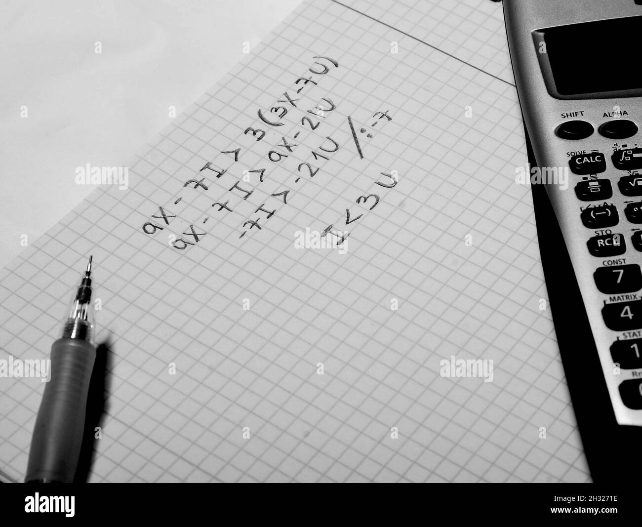 Penna, calcolatrice scientifica e carta con un'equazione risolta Foto Stock