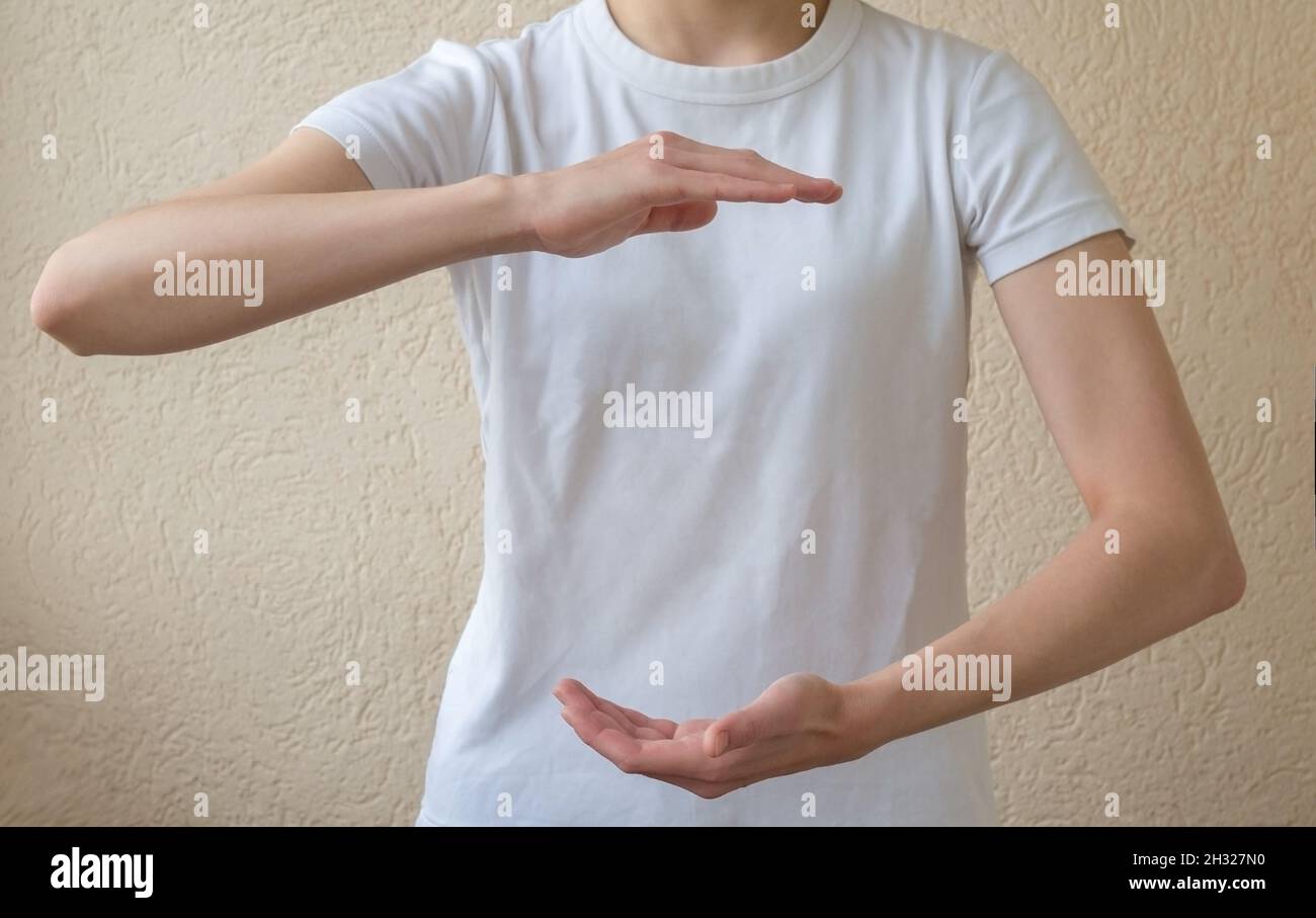 Layout per l'inserimento del testo. Una donna in una T-shirt bianca che tiene qualcosa sui palmi delle mani aperte. Spazio di copia per l'oggetto. Foto Stock