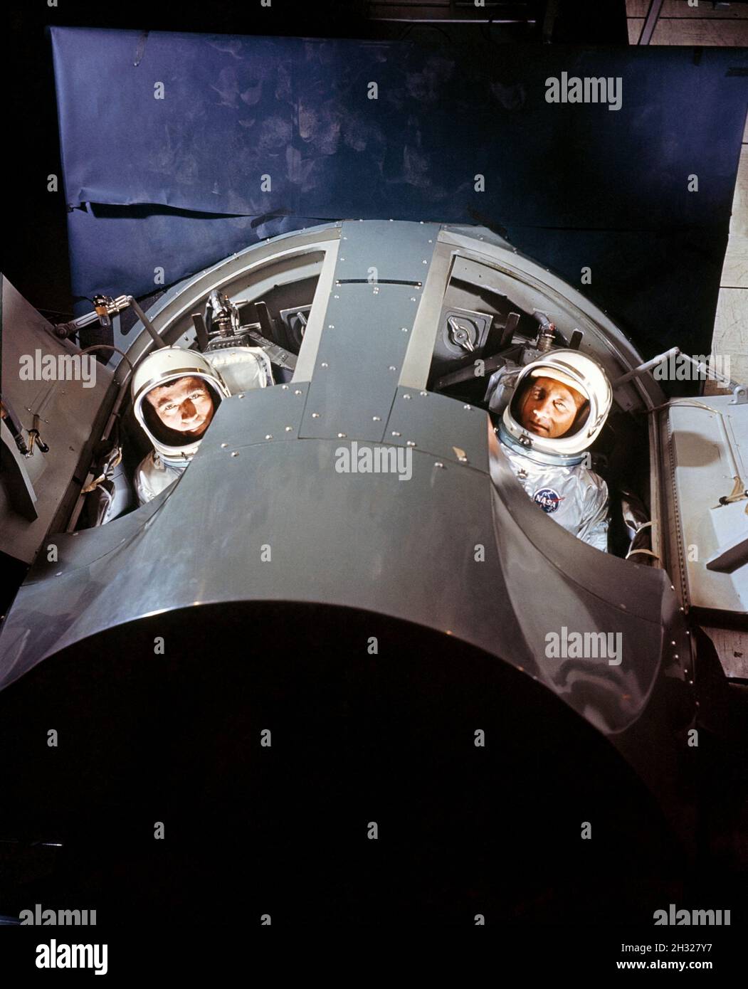 (Marzo 1964) --- gli astronauti Virgil I. (Gus) Grissom (a destra) e John W. Young, primo equipaggio per la prima missione Gemini presidiata (GT-3), sono mostrati all'interno di un simulatore di missione Gemini presso McDonnell Aircraft Corp., St. Louis, MO. Il simulatore fornirà agli astronauti Gemini e agli equipaggi di terra una simulazione realistica della missione durante l'allenamento intensivo prima del lancio effettivo. Foto Stock
