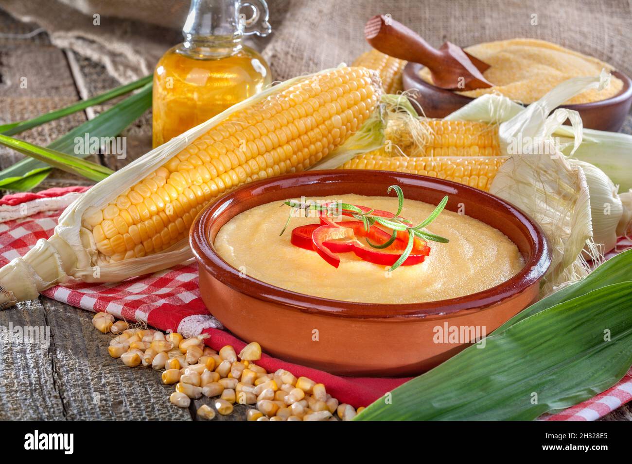 Polenta di mais in ciotola di legno con olio vegetale Foto Stock