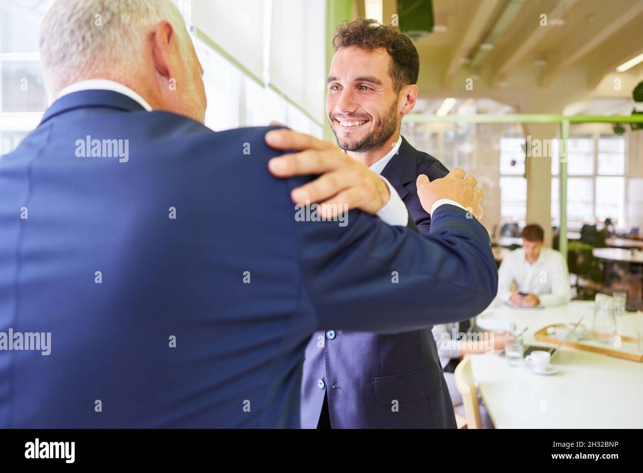 Due uomini d'affari si salutano con un abbraccio o celebrano una buona collaborazione Foto Stock