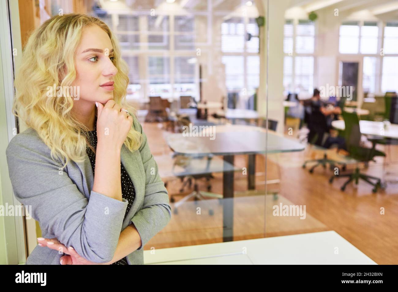 Giovane donna come una pensierosa donna d'affari o tirocinante in un ufficio open plan Foto Stock