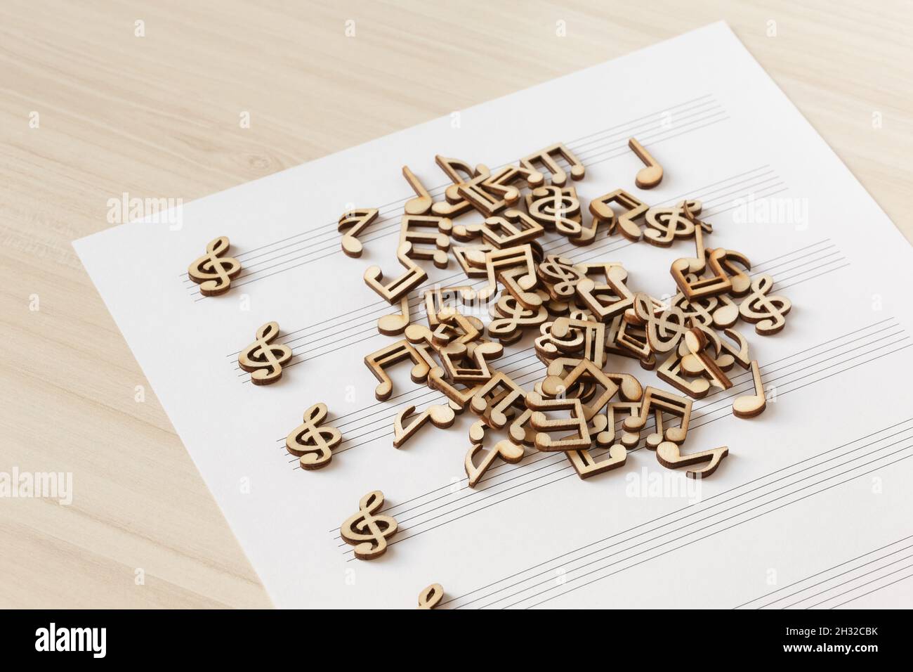 Caotica pila di note musicali in legno adagiata su un foglio di musica Foto Stock