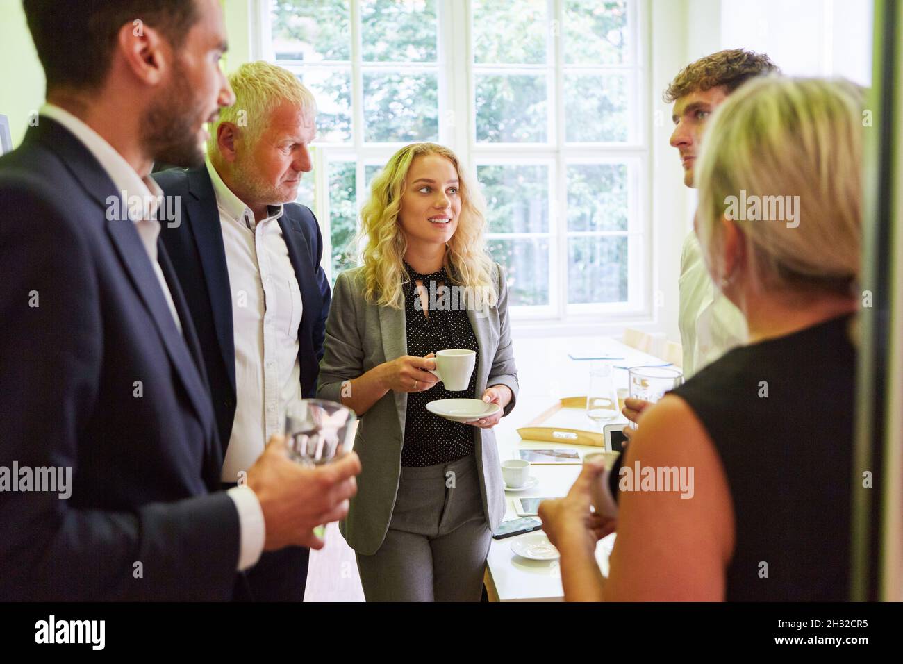 Gruppo di uomini d'affari che hanno un piccolo colloquio durante la pausa caffè dopo una riunione Foto Stock