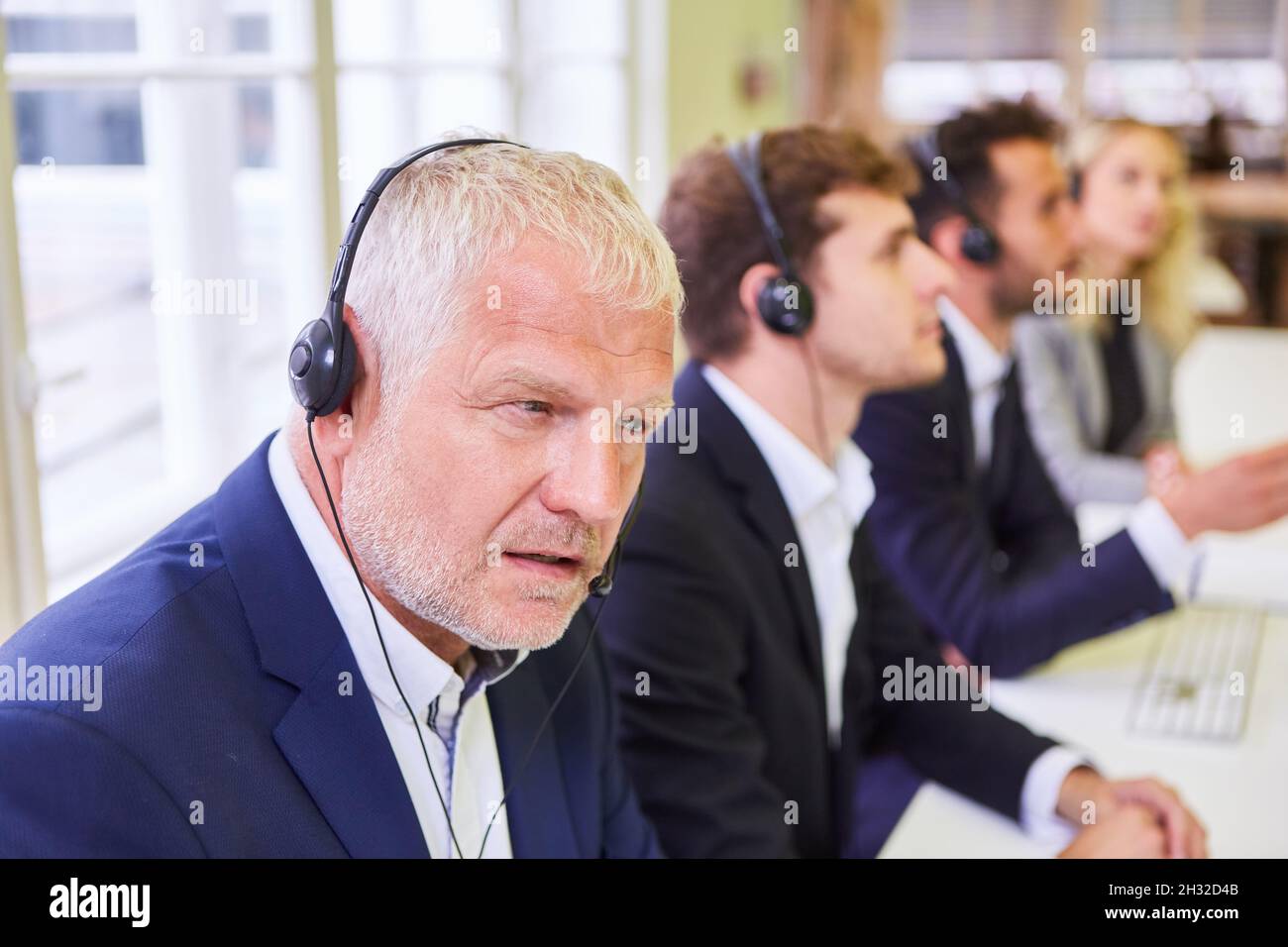 Gruppo di uomini d'affari con cuffie durante la formazione nel call center o nel corso di lingua Foto Stock