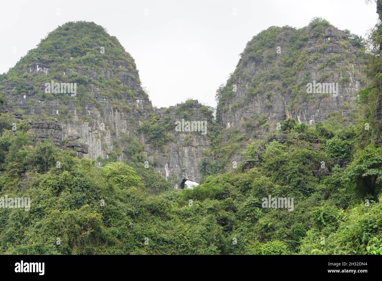 Guarda una montagna con un buco durante Trang An giro in barca, Ninh Binh, Vietnam Foto Stock