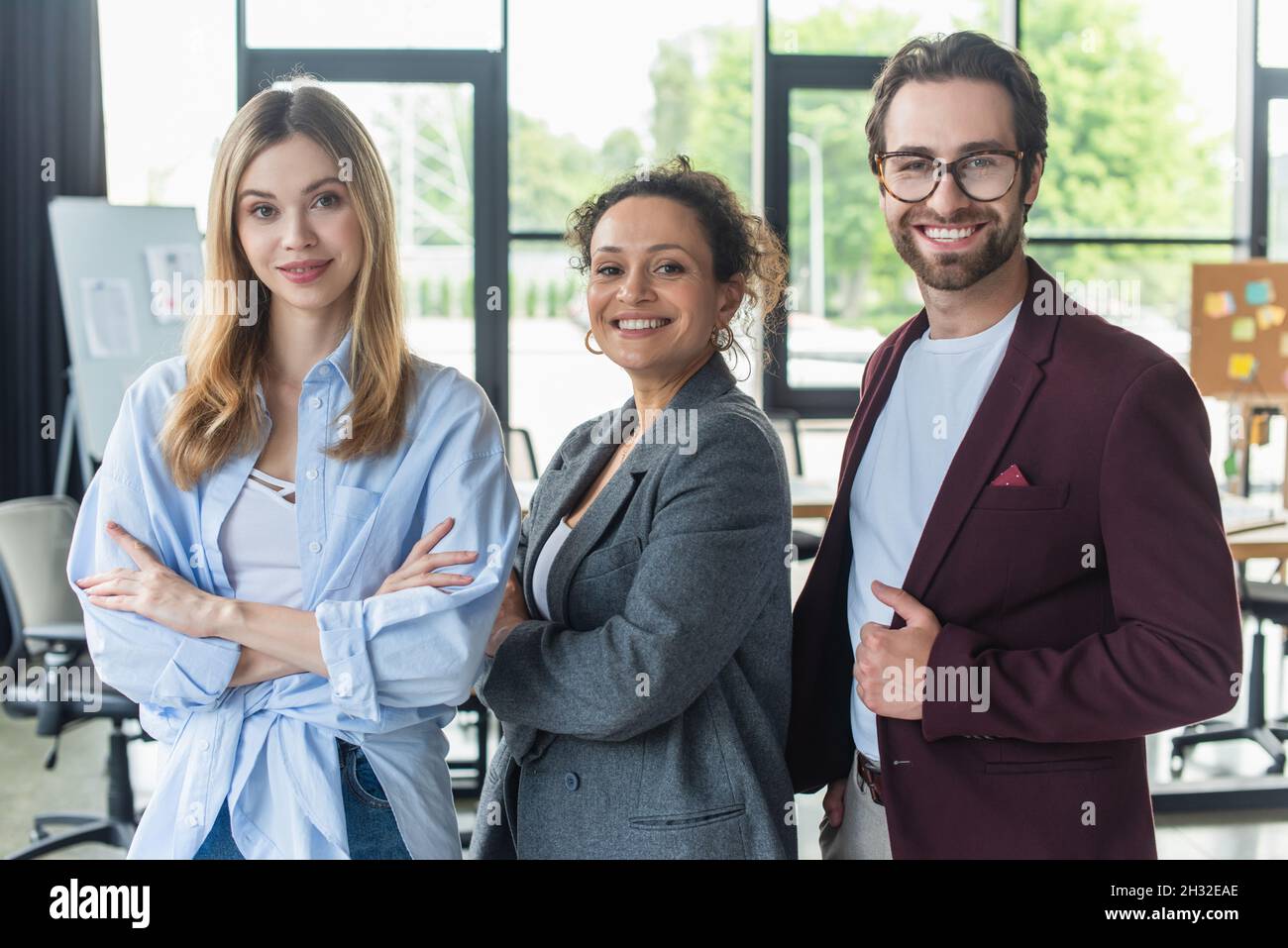 Uomini d'affari multietnici sorridenti alla macchina fotografica in ufficio Foto Stock