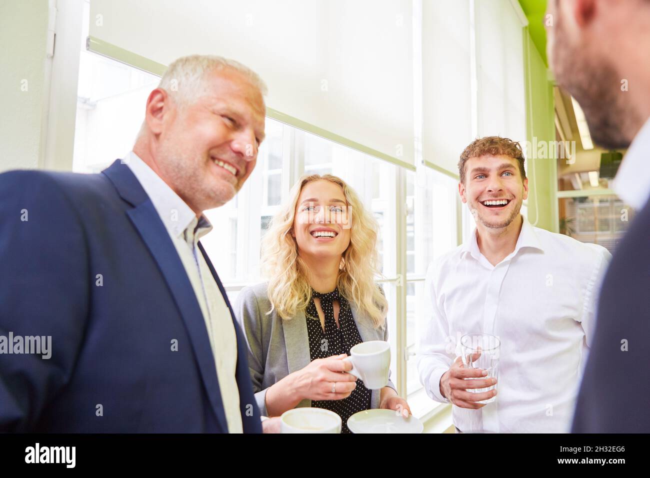 I colleghi del team aziendale in ufficio si divertono durante una pausa caffè mentre parlano poco Foto Stock