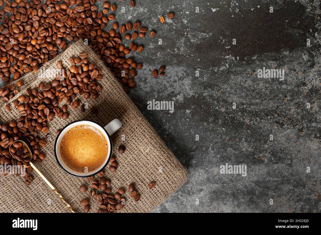 una tazza di caffè con una bella schiuma poggia su un tessuto su uno sfondo  di cemento, i chicchi di caffè sono sparsi nelle vicinanze. spazio copia  Foto stock - Alamy