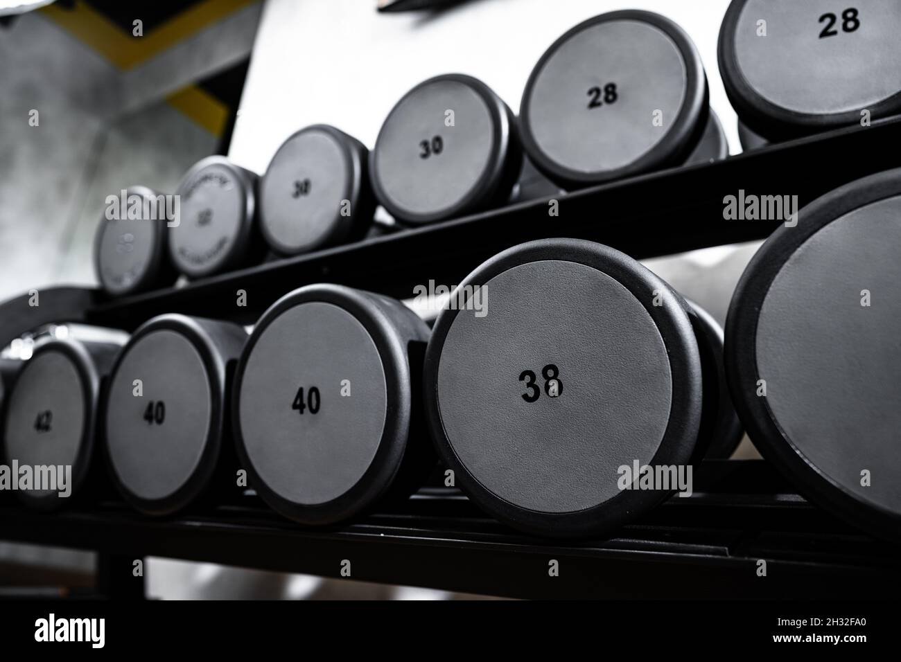 File di manubri in metallo su rack per bodybuilding in palestra Foto Stock