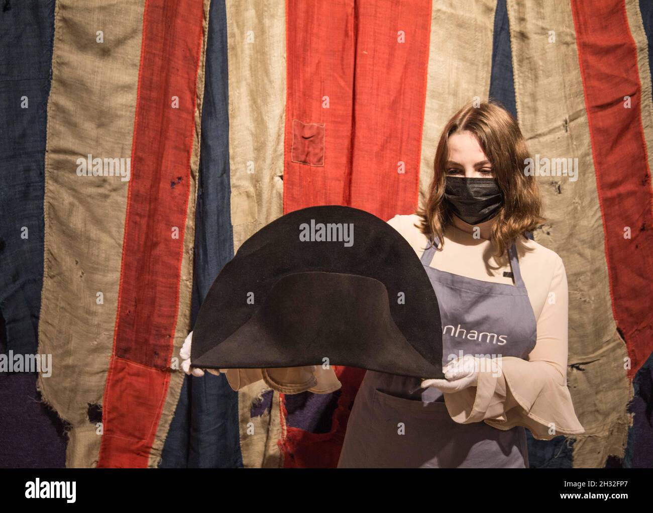 Londra UK 25 Ottobre 2021 un cappello Bicorne creduto essere indossato da Napoleone Bonaparte, attribuito a Poupart & Cie, Parigi, circa 1806-07. Preventivo: £100,000 - 150,000 davanti ad Una bandiera rara e grande dell'Unione Jack ed il pennant, probabilmente da HMS Temeraide ,Circa 1810,fatto da Bunting Paul Quezada-Neiman/Alamy Live News Foto Stock