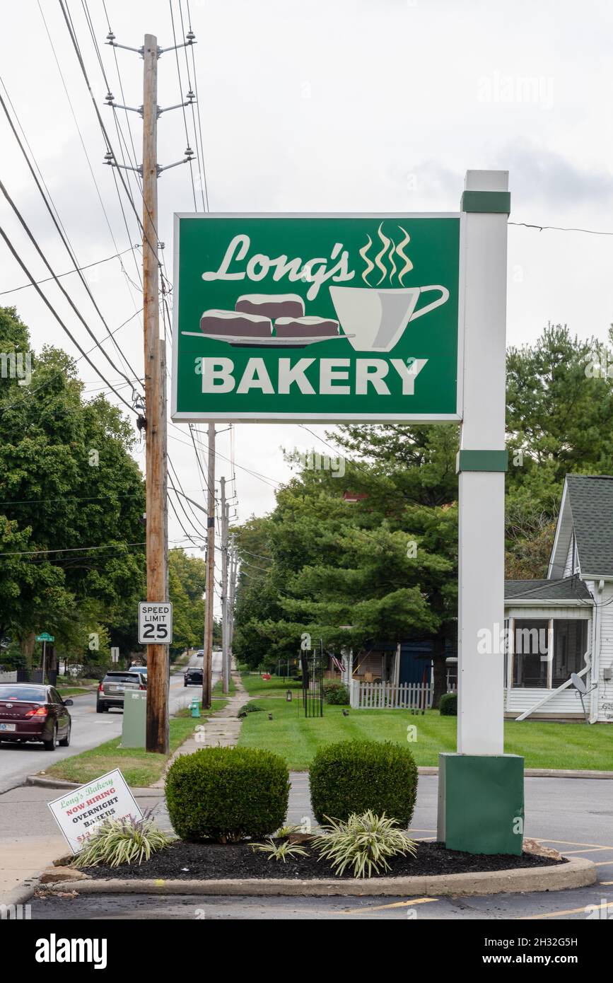 Un alto cartello verde con un'immagine di ciambelle e una tazza di caffè pubblicizza la popolare panetteria Long's a Southport, Indiana. Foto Stock