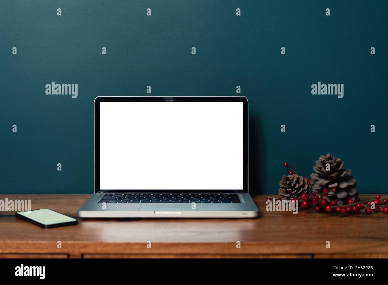Computer portatile con schermo vuoto mockup su un moderno design smeraldo del soggiorno. Ufficio domestico, posto di lavoro, lavoro o studio da casa, distanza Foto Stock