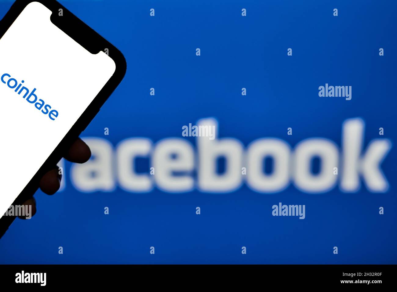 Tashkent, Uzbekistan - 22 Ottobre, 2021: Tenere a mano il telefono cellulare con il logo Facebook sopra il logotipo Coinbase sullo sfondo. Facebook collabora con Foto Stock