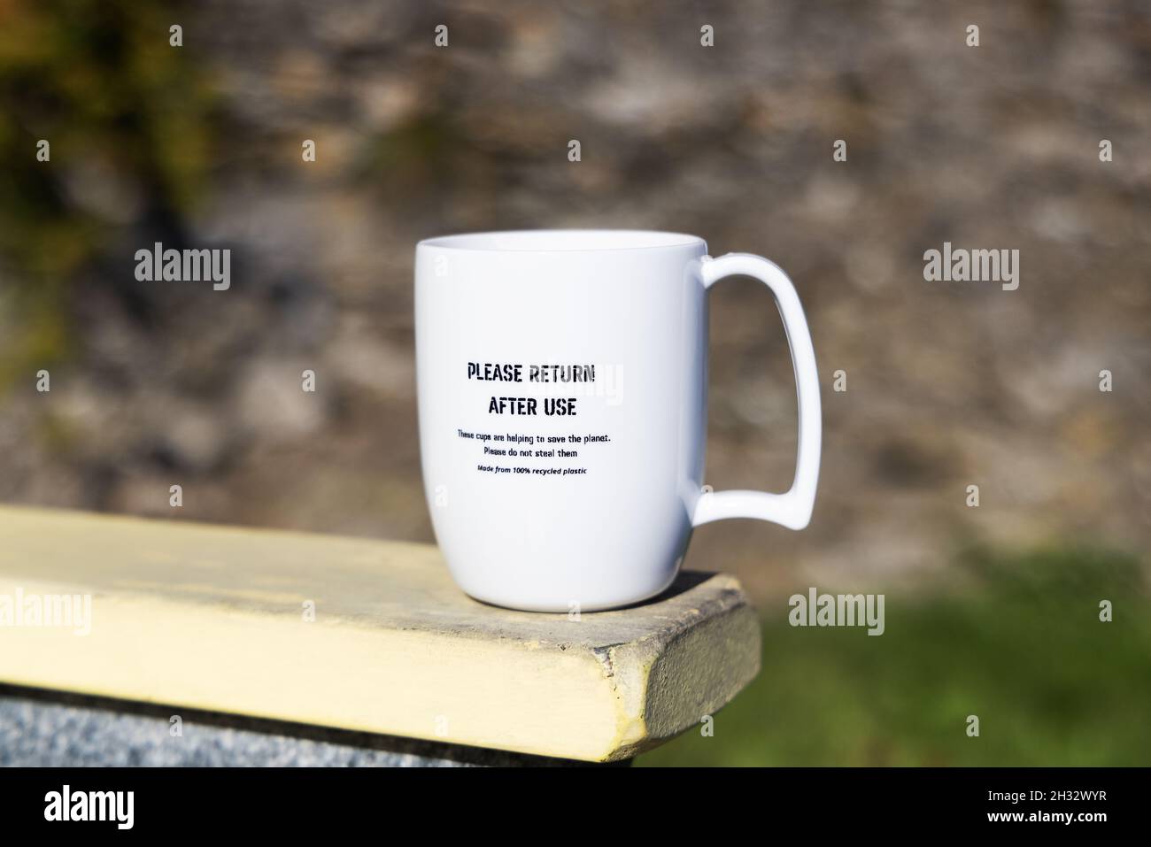 "Save the Planet" - Una tazza di caffè riutilizzabile in plastica con scritta "Please return after use" (si prega di restituire dopo l'uso), per essere riutilizzata in un bar, Fowey, Cornwall UK Foto Stock