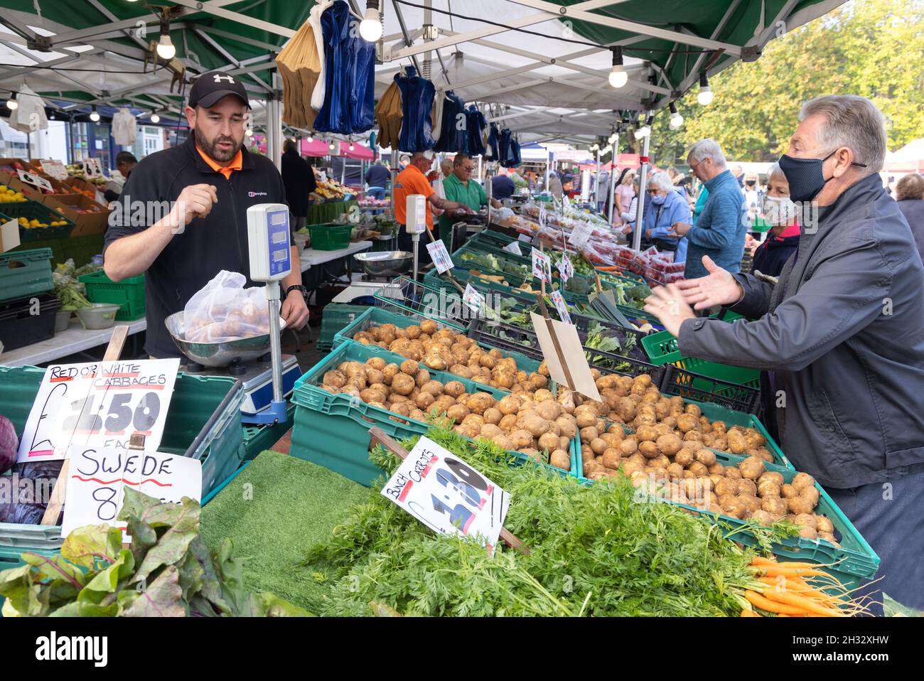 Greengrocer stalla UK, vendita di verdure a un cliente in una maschera durante la Pandemic COVID 19, Salisbury mercato, Salisbury Wiltshire Regno Unito Foto Stock