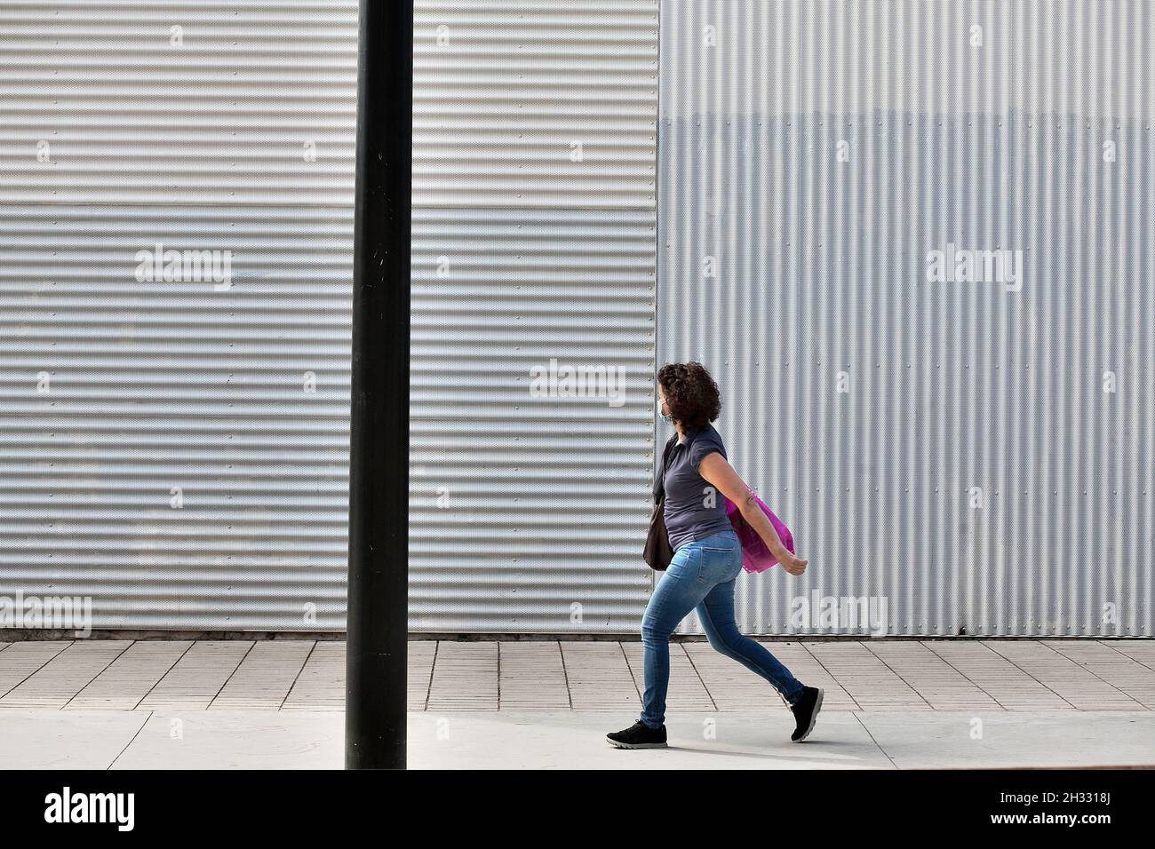 Donna che cammina per strada indossando maschera, Barcellona, Spagna Foto Stock