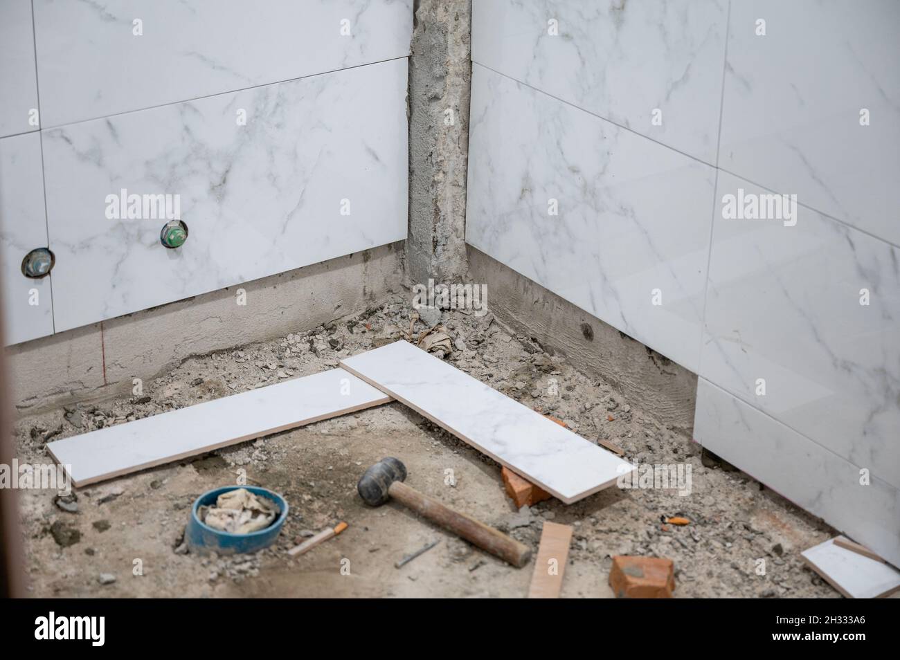 Riparazione e ristrutturazione, parete del bagno con piastrelle e utensili in marmo piastrellato Foto Stock